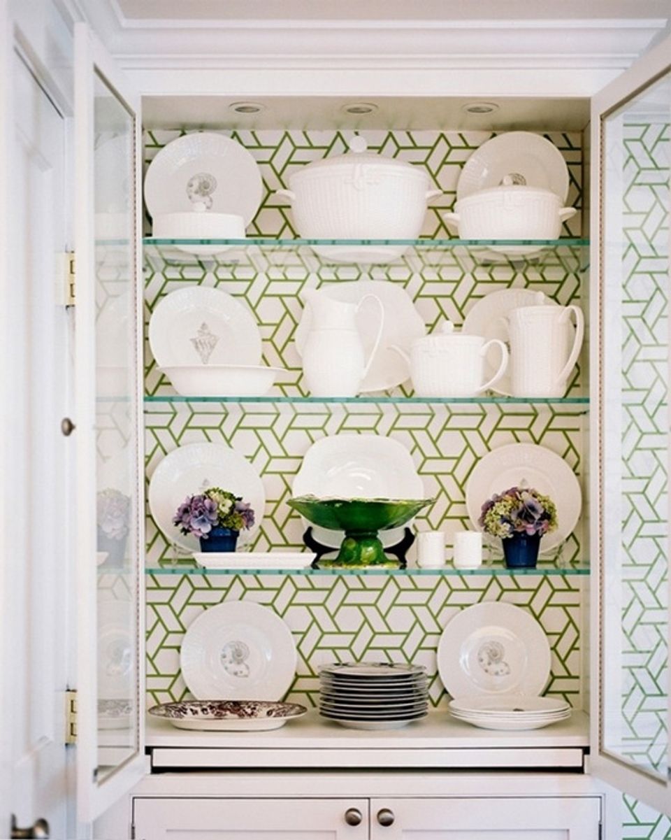 Elegant china cabinet with geometric green and white peel-and-stick wallpaper backing