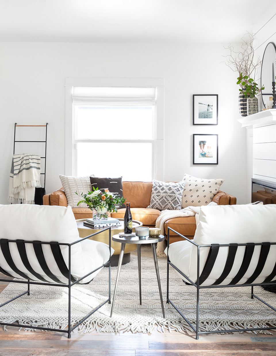 Contemporary eclectic seating area blending warm cognac leather, black striped chairs, and geometric patterned cushions