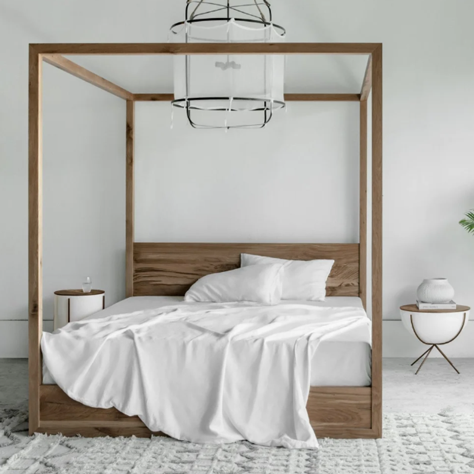Contemporary walnut canopy bed with integrated headboard in serene white bedroom
