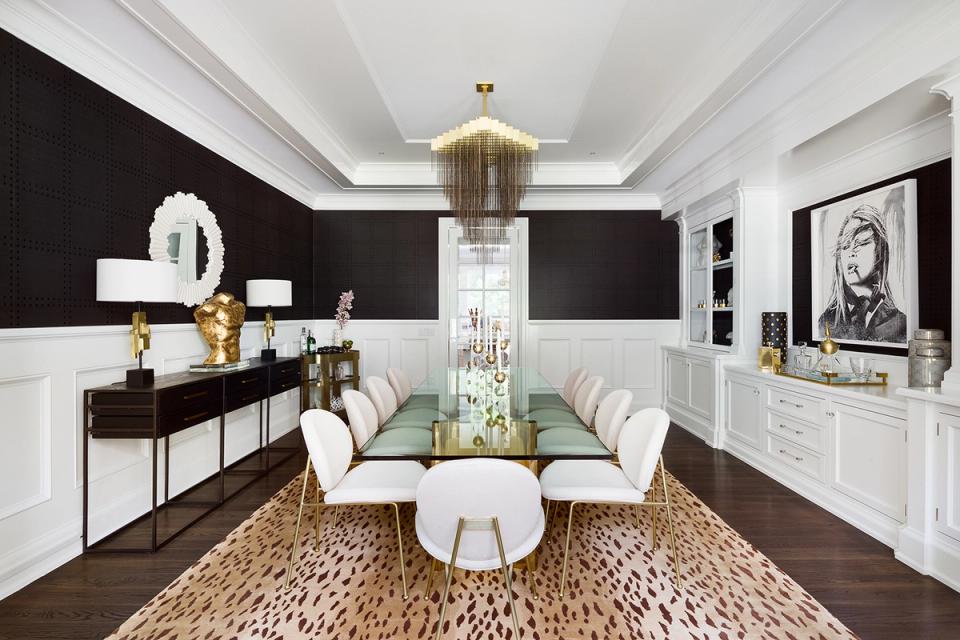 Glamorous dining room with black and white color blocking, statement chandelier, and modern elegance with gold accents