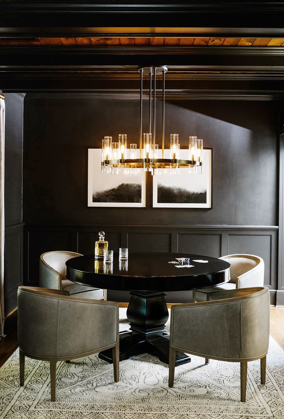 Dramatic dining space with black paneling, brass chandelier, curved sage chairs, and moody elegance for sophisticated entertaining.