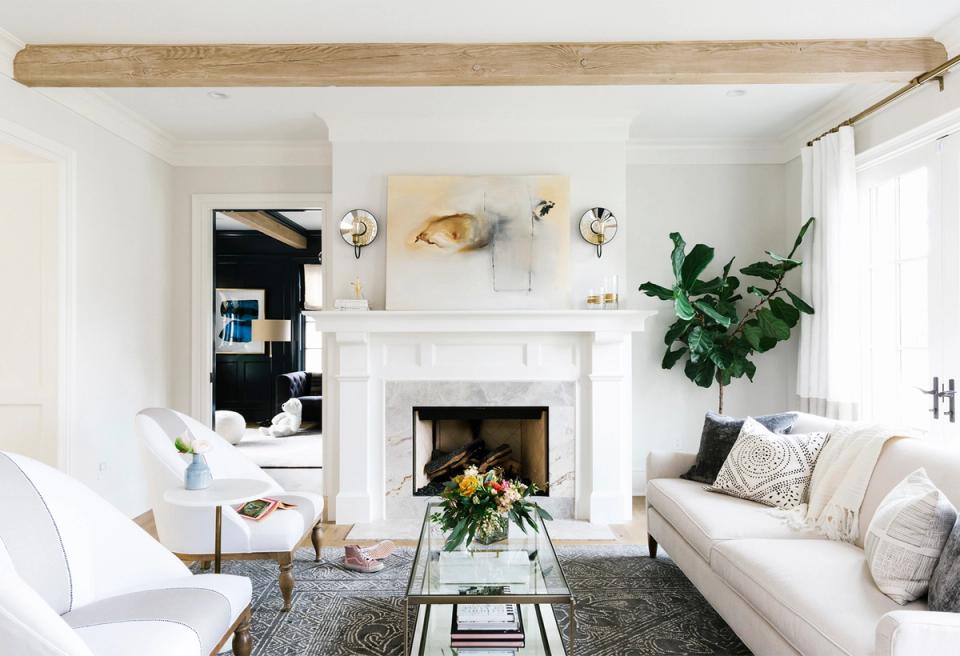 Bright, minimalist living room with white fireplace, neutral furnishings, and balanced scale between statement pieces and negative space