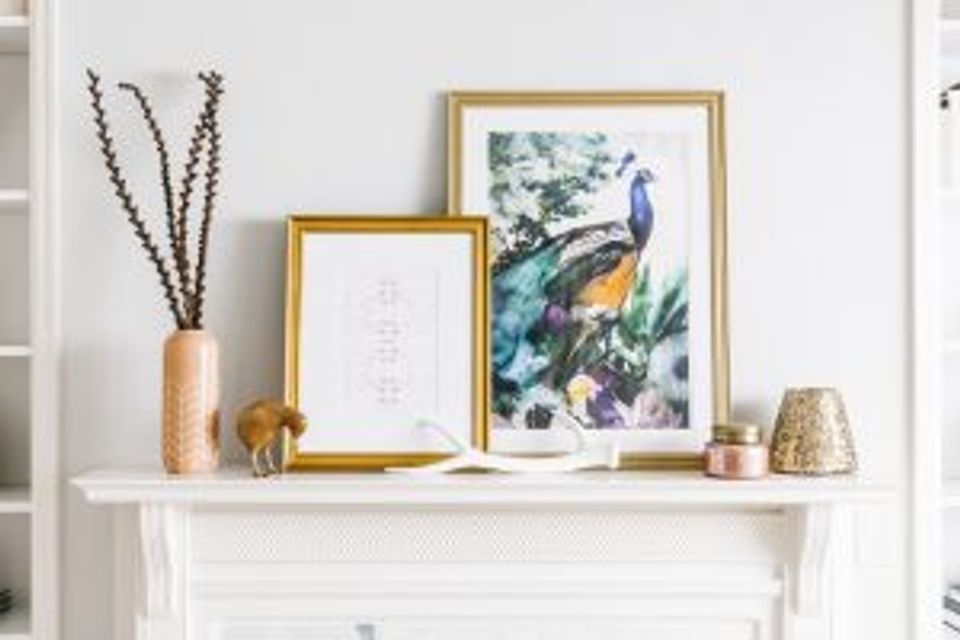Serene mantel display with gold-framed botanical artwork, dried botanicals, and coastal décor styling