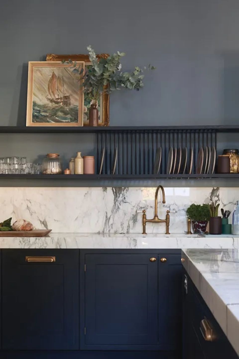 Contemporary kitchen with dark gray-blue walls, marble backsplash, and brass fixtures creating refined elegance