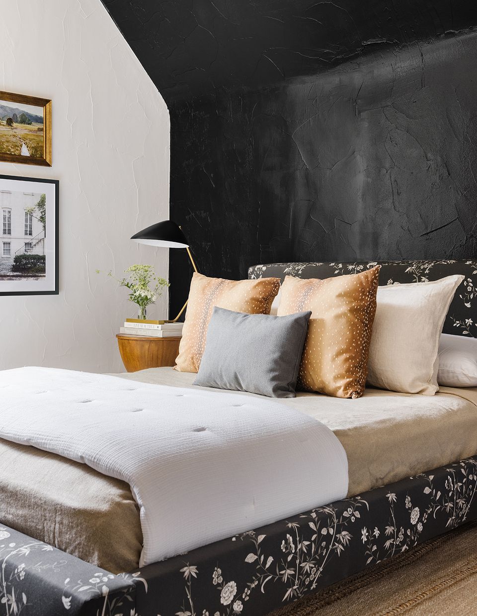 Contemporary bedroom with dramatic black headboard, warm gold and cream pillows, and soft white bedding.