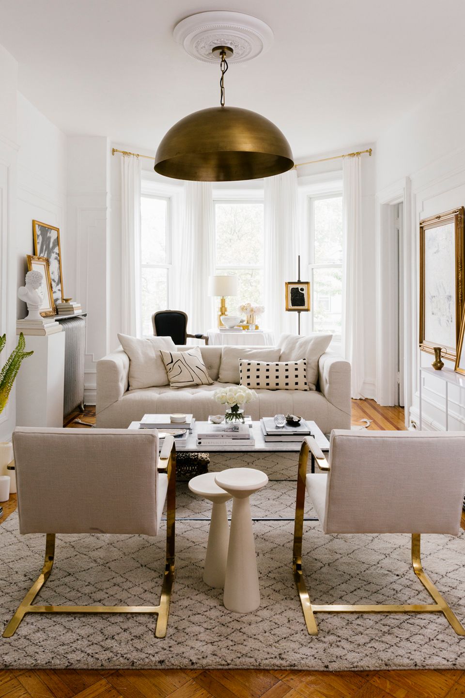 Elegant transitional living room with geometric cream rug and brass dome pendant light
