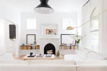 Minimalist Scandinavian fireplace nook with crisp white walls, black pendant light, and natural wood shelving in serene, contemporary style