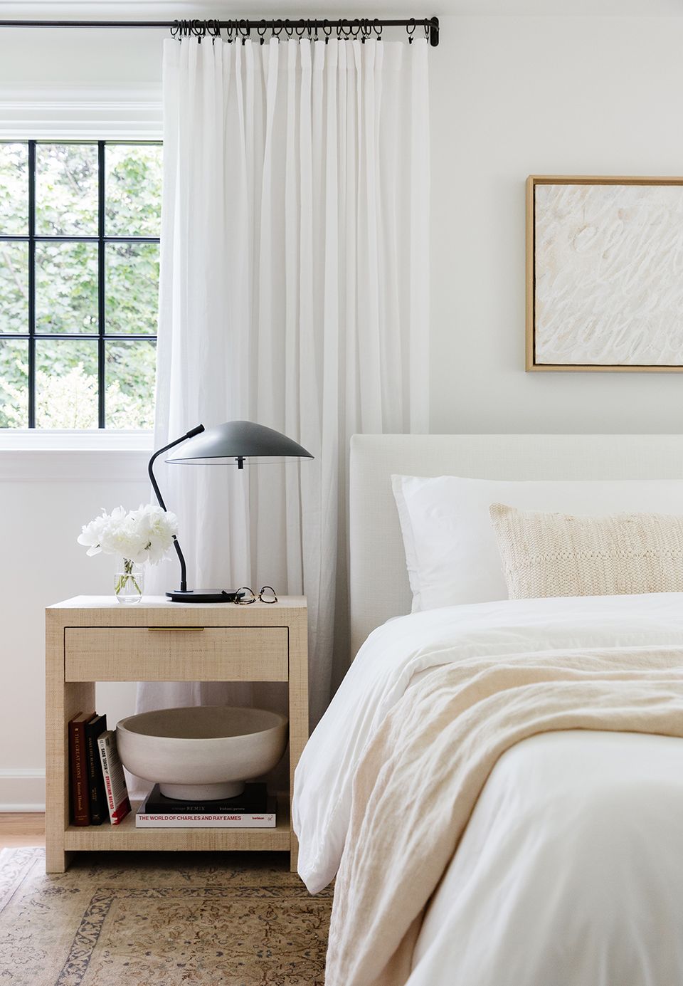 Serene bedroom with warm wood nightstand, cream striped bedding, black arc lamp, and soft neutral tones