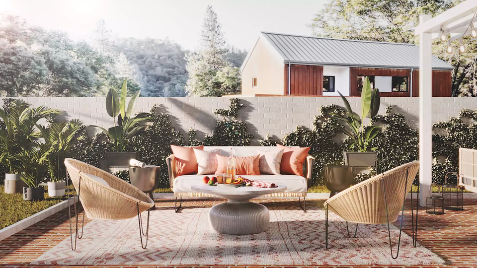 Mid-century modern backyard with coral cushioned sofa, woven chairs, and potted plants creating a warm, inviting outdoor living space.