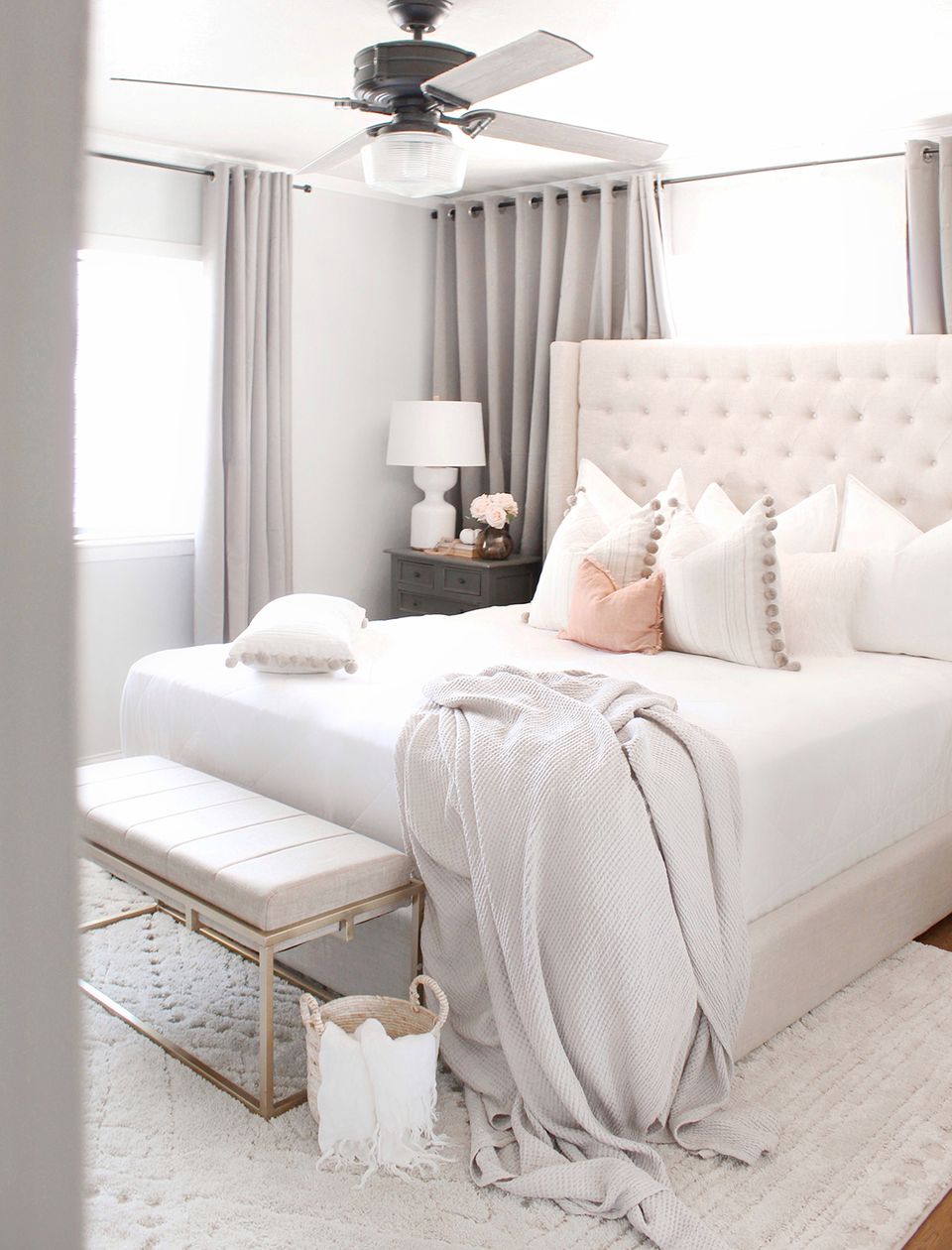 Serene neutral bedroom with quilted cream headboard, soft pink accents, and minimalist aesthetic