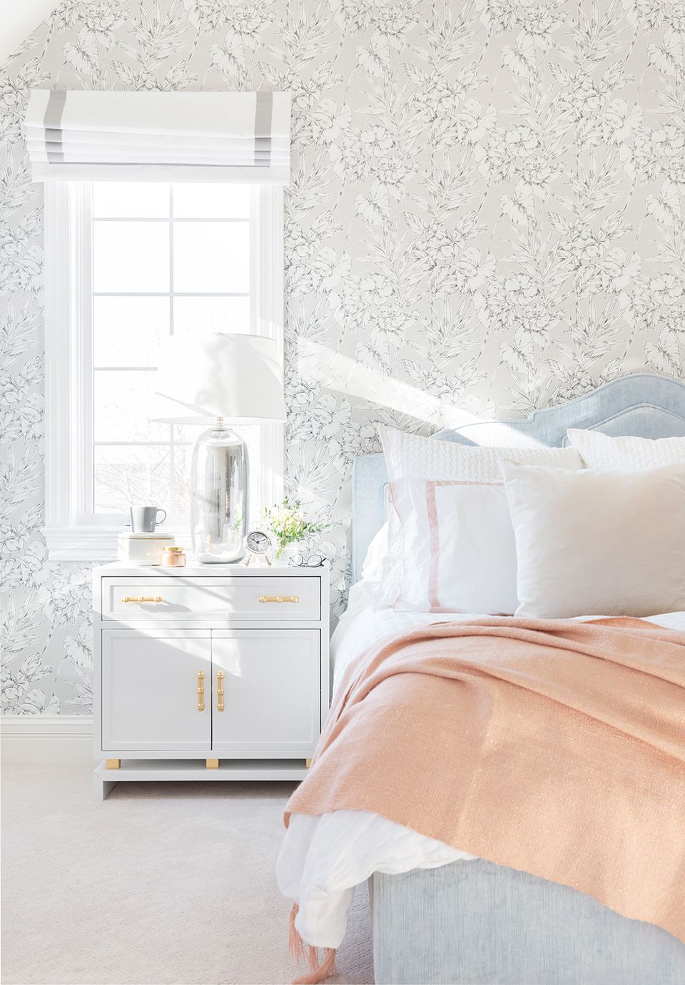 Soft romantic bedroom with delicate floral wallpaper, pale blue headboard, and peachy linens evoking a dreamy feminine mood