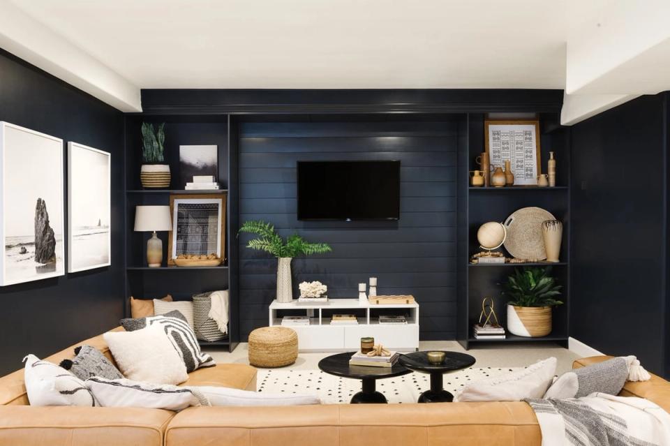 Modern living room with navy shiplap accent wall, built-in shelving, and floating TV console in warm wood tones with natural decor.