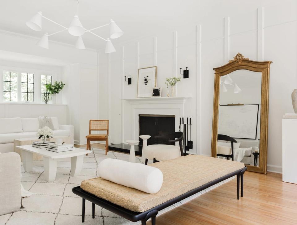 Bright minimalist living room with tall white wainscoting, warm wood accents, and clean modern aesthetic