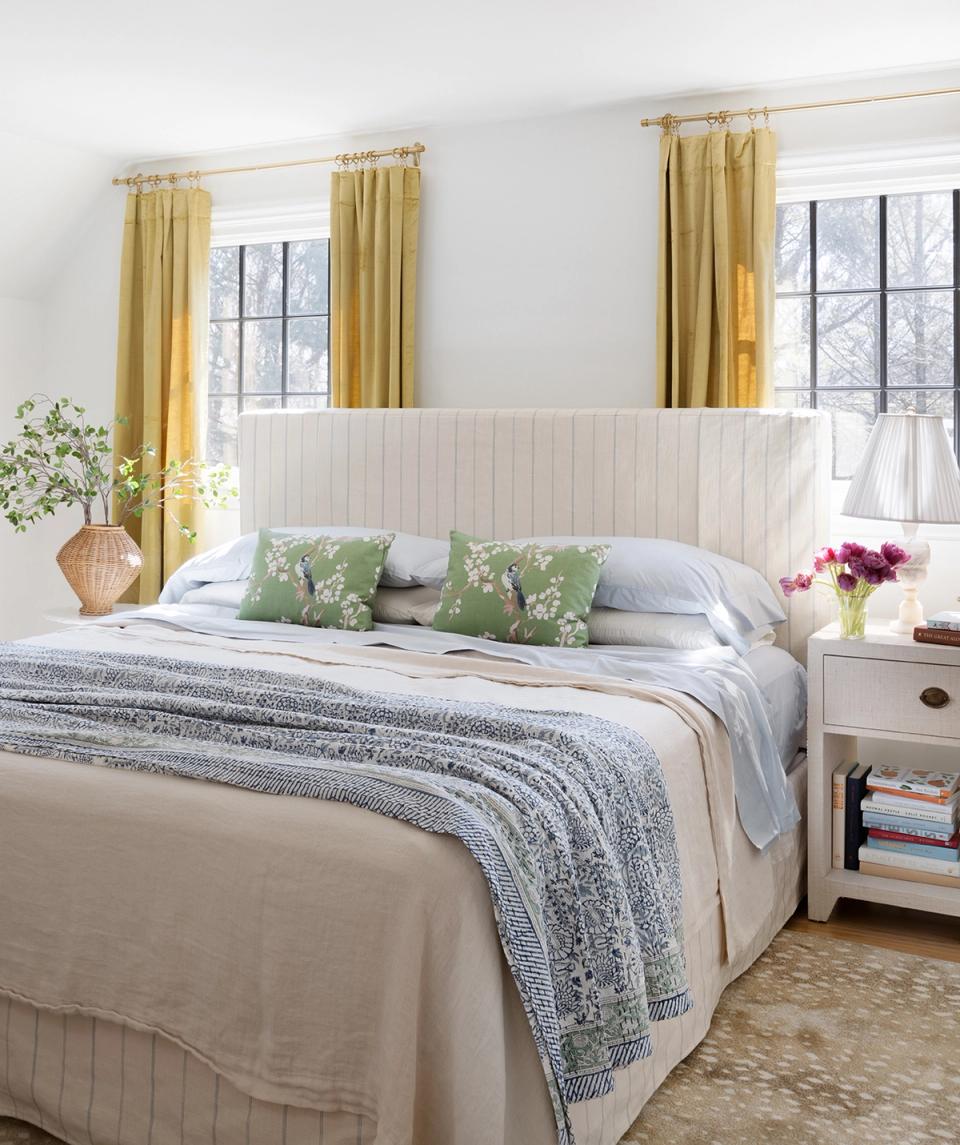 Bright farmhouse bedroom with cream headboard, gold curtains, and fresh green accent pillows