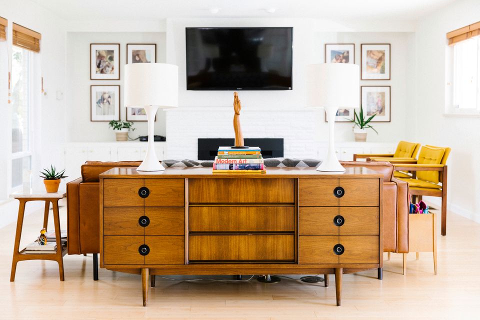 Warm mid-century media console in rich wood with mustard accents and gallery wall styling