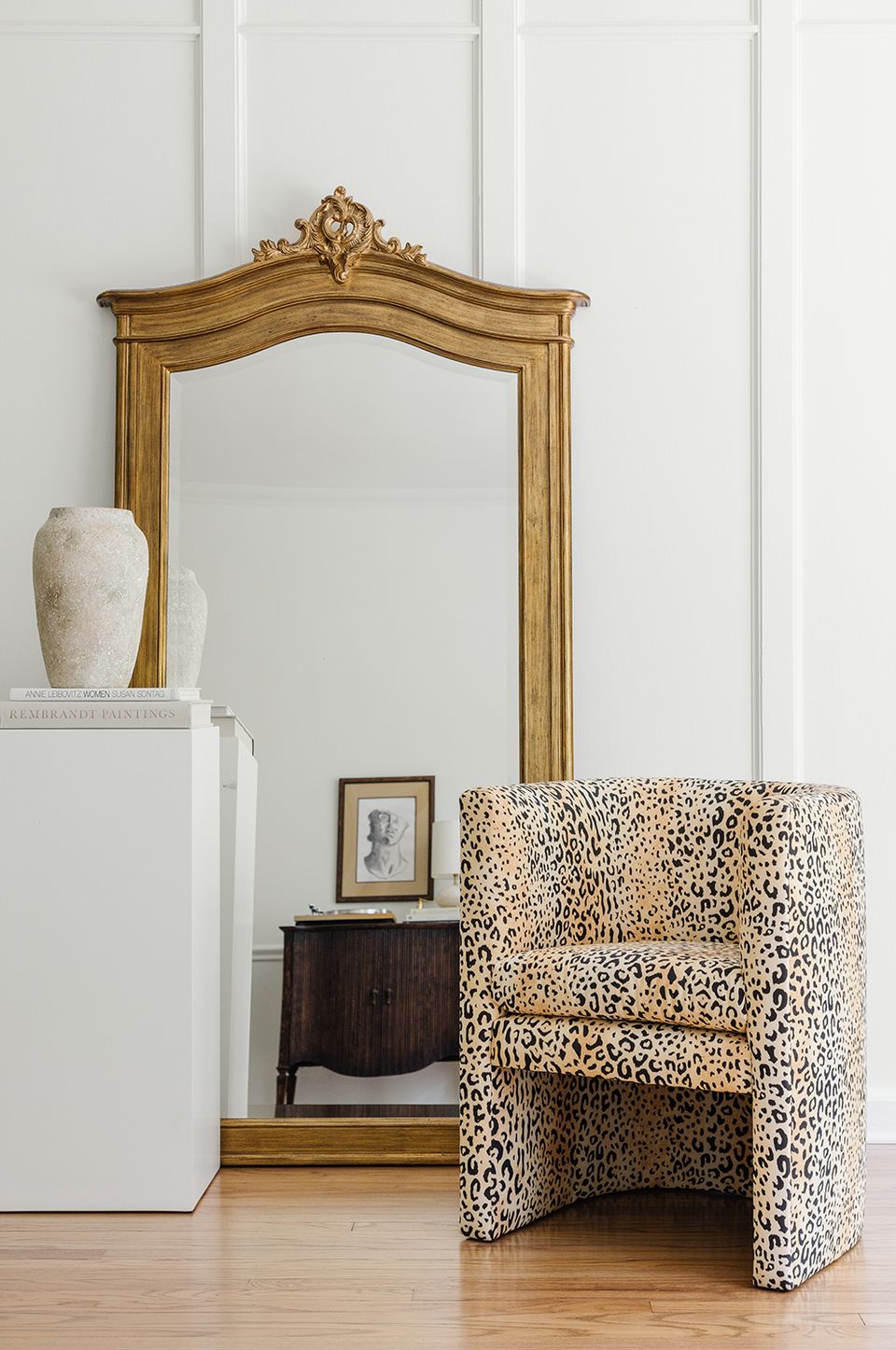 Ornate gilt mirror paired with modern textured accent chair in serene neutral space