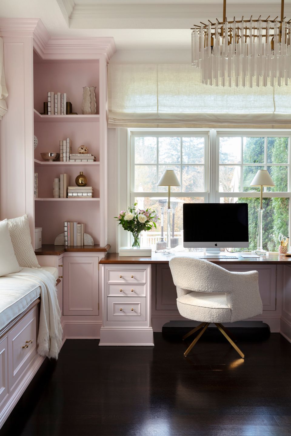 Feminine home office in soft mauve with built-in shelving, natural light, and elegant traditional styling