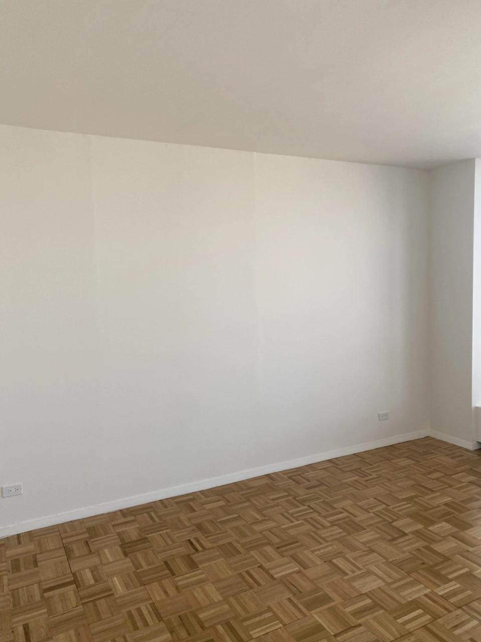 Clean minimalist room with natural wood herringbone flooring and bright white walls