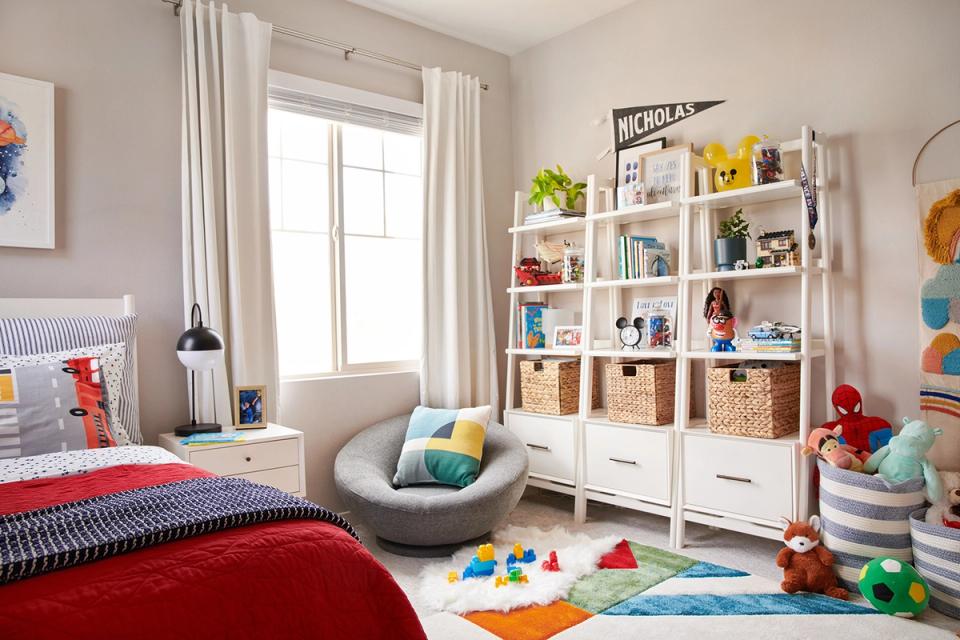 Bright kids' bedroom with colorful toy storage cubbies, red accents, and organized shelving for playful, functional design.