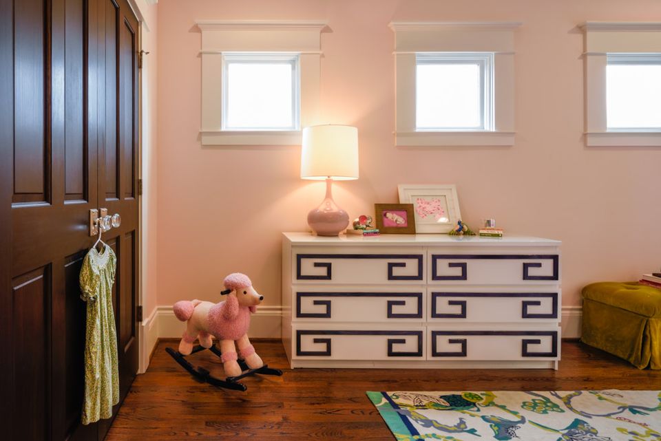 Cheerful nursery corner featuring geometric dresser, warm peach walls, soft lighting, and playful colorful accents.