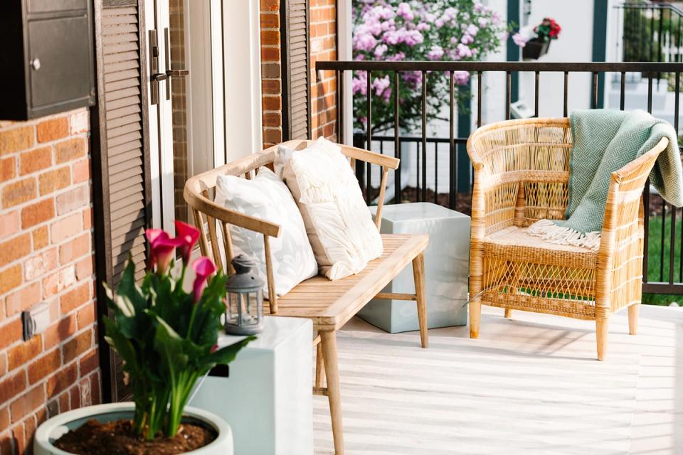 Bright coastal-inspired deck with wicker chairs, cream cushions, and flowering plants in soft, welcoming tones.