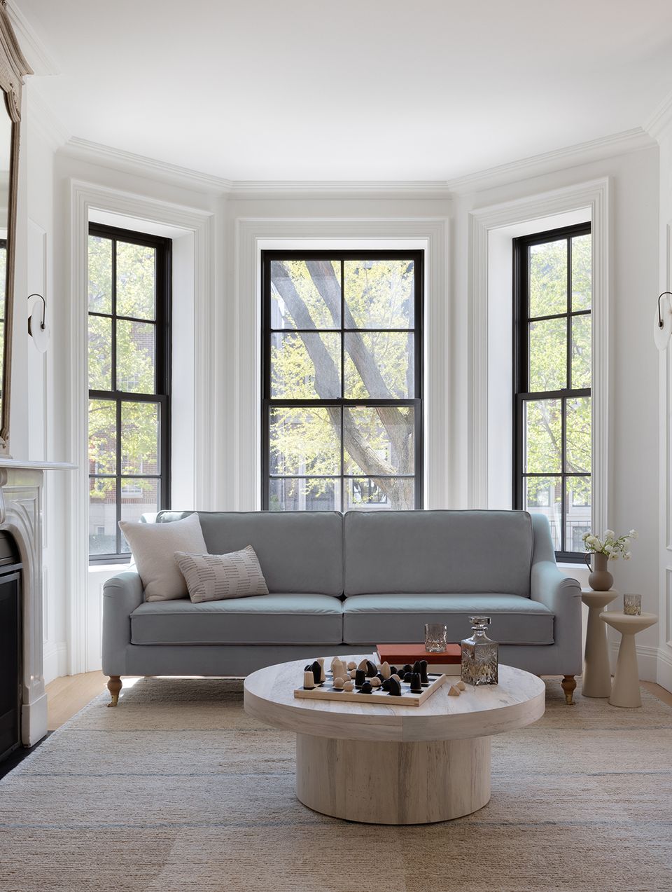 Contemporary minimalist room with gray sofa, light wood table, and black-trimmed windows