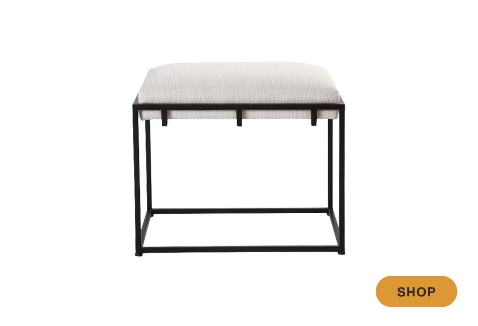 Minimalist end-of-bed bench with black metal frame and cream upholstered seat, featuring clean lines and industrial-contemporary design.
