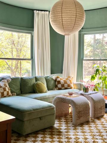 Sage green curved seating nook with cream curtains and natural textures