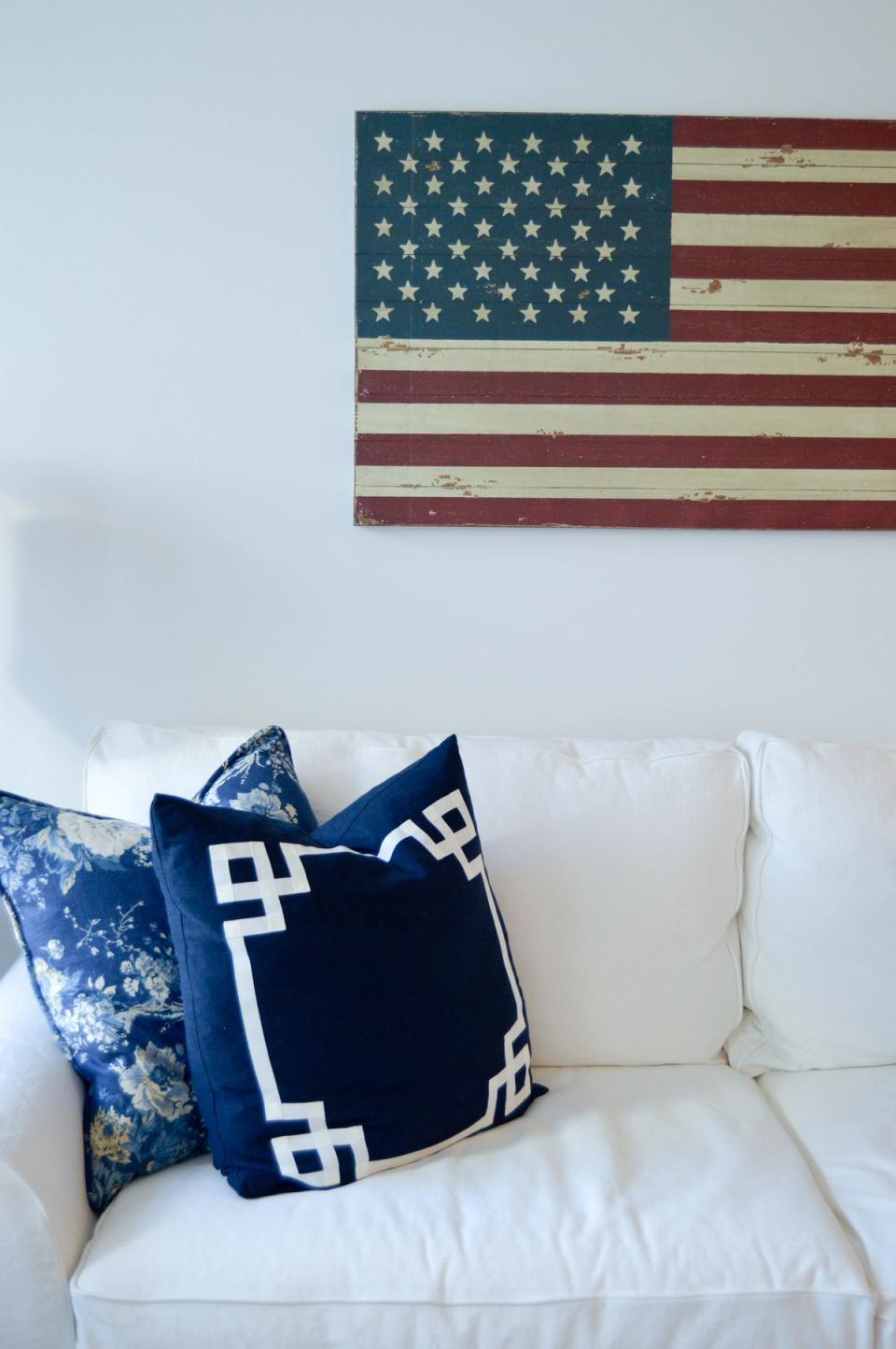 Nautical-inspired seating with cream sofa, navy geometric pillow, and distressed flag wall art