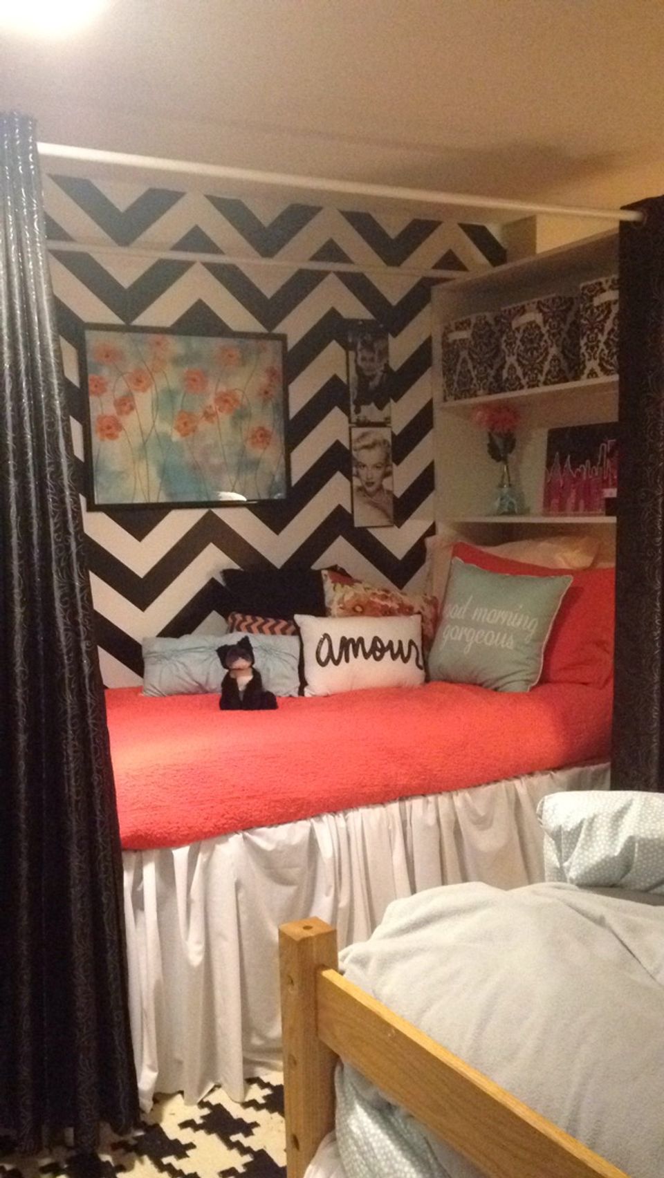 Bold geometric chevron loft bed in black and white with coral bedding and patterned accents for vibrant small space