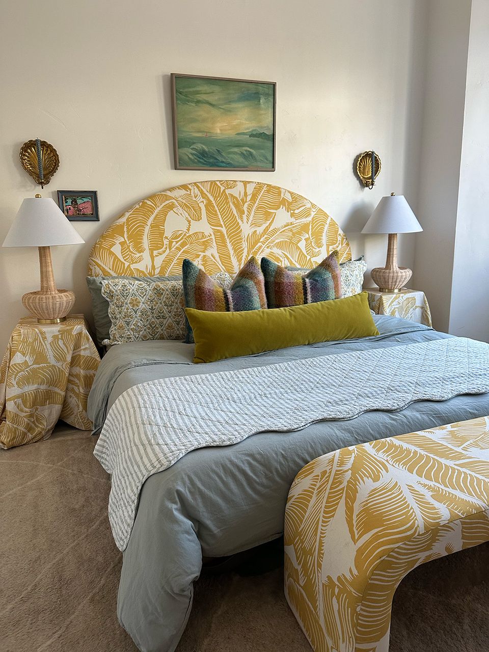 Maximalist bedroom with golden botanical headboard, layered patterned pillows, and warm neutral palette