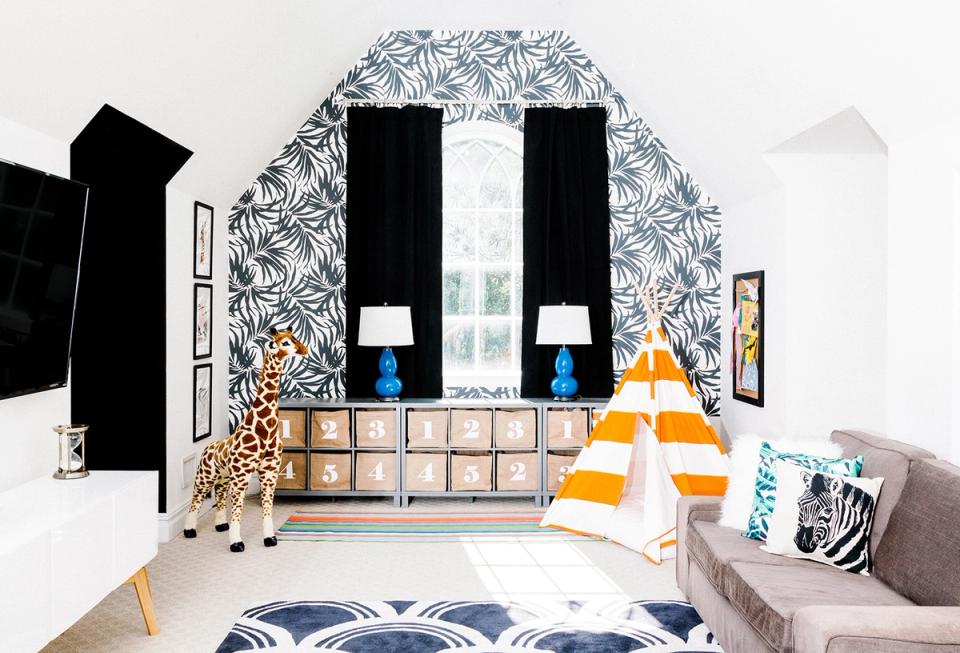 Eclectic bedroom with bold botanical wallpaper, black accents, and mixed-material storage