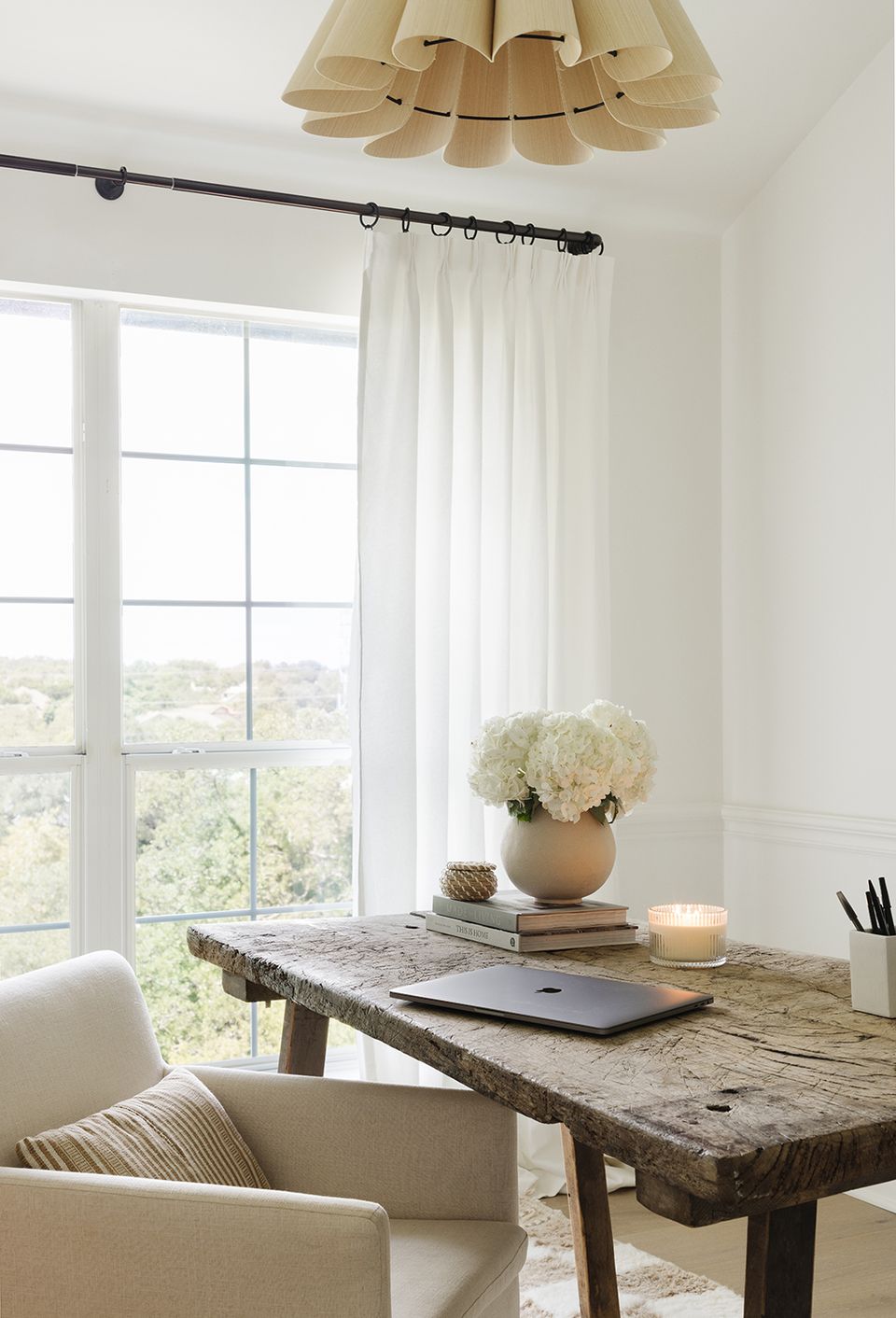 Minimalist sunroom with natural wood desk, neutral palette, and sculptural pendant light