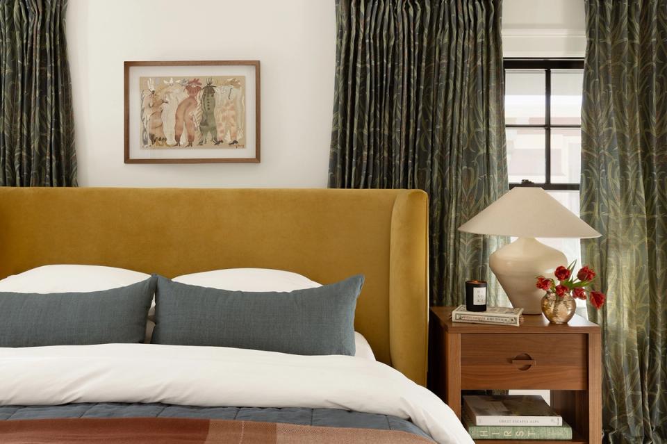 Mid-century bedroom with mustard upholstered headboard, sage green curtains, and warm wood nightstand