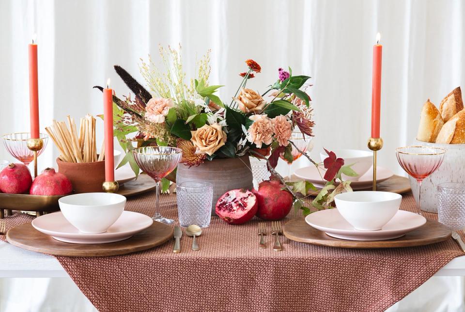 Warm terracotta and blush holiday table with peach florals, coral candles, and textured linens