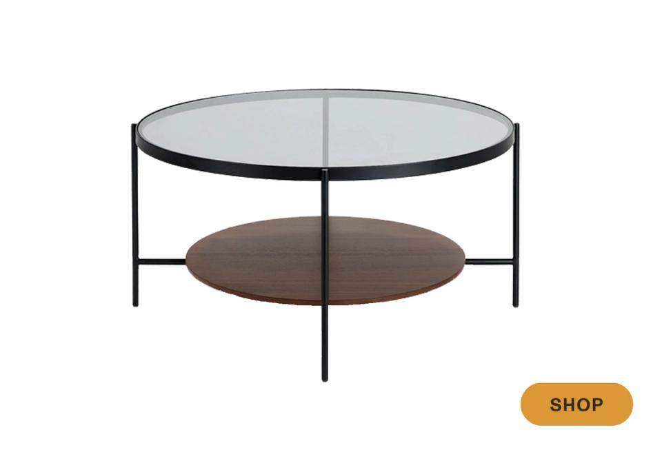 Modern two-tier round coffee table with glass top, dark metal frame, and wood shelf