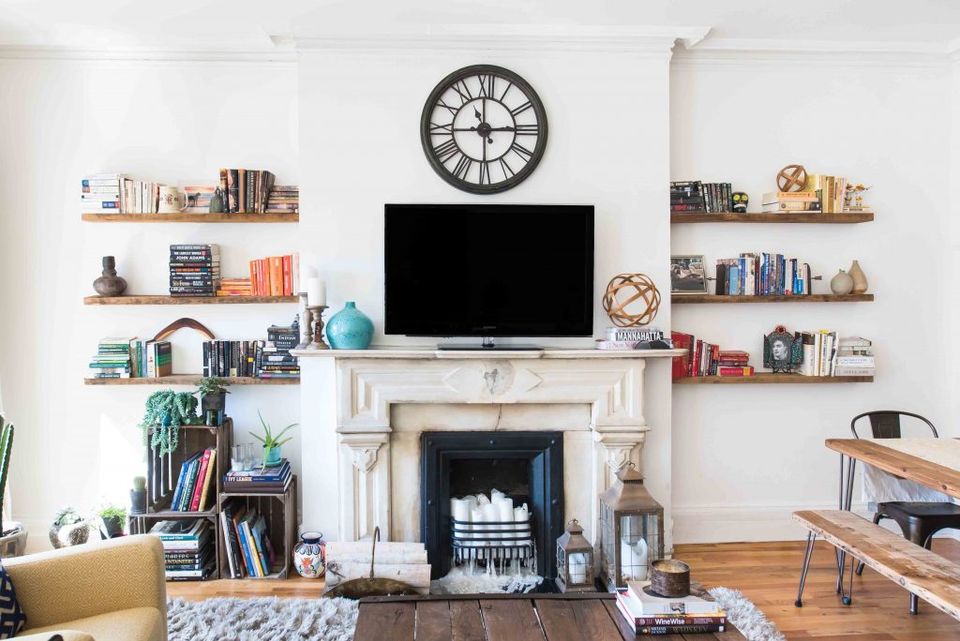Transitional living room with fireplace, floating shelves, and collected books in warm neutral tones