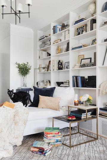 Modern minimalist bedroom library with floor-to-ceiling shelving, crisp whites, and navy accents creating calm retreat.