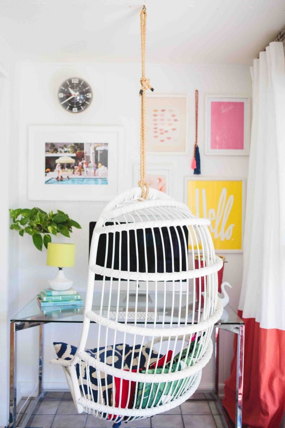 Cheerful bedroom corner with white hanging chair, colorful gallery wall, and playful style