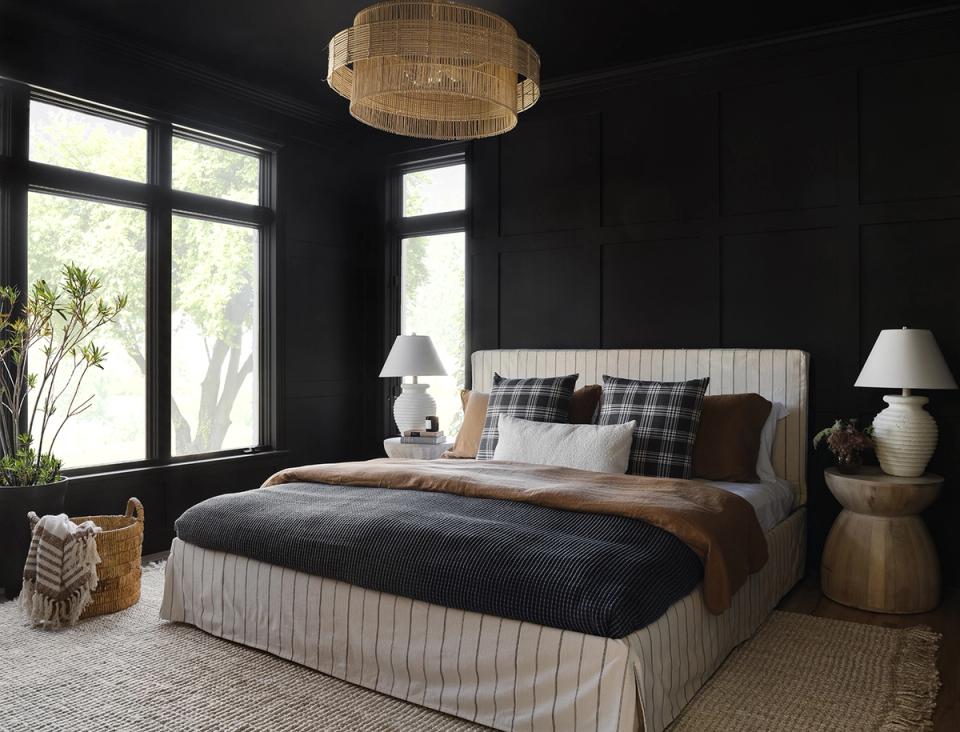 Bold black bedroom with cream striped bed, warm wood tones, and dramatic modern luxury