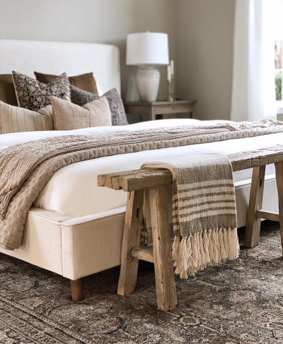 Neutral boho bedroom with linen textures, woven bench, and earthy striped layering