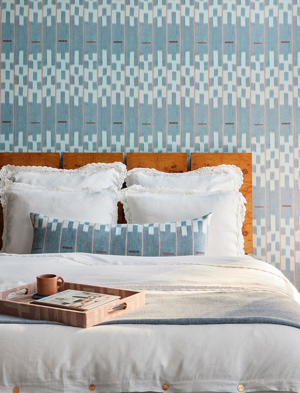 Serene boho bedroom with geometric patterned wallpaper, wooden headboard, and soft blue accents