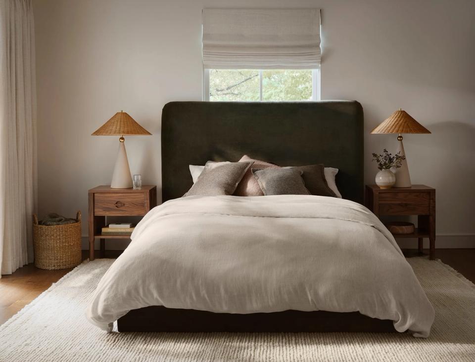 Transitional bedroom design with charcoal upholstered headboard, cream linens, warm wood nightstands, and earthy neutral color scheme