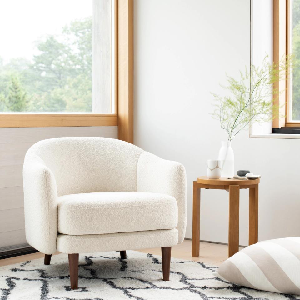 Scandinavian-inspired seating area with cream boucle chair, natural wood accents, and geometric rug