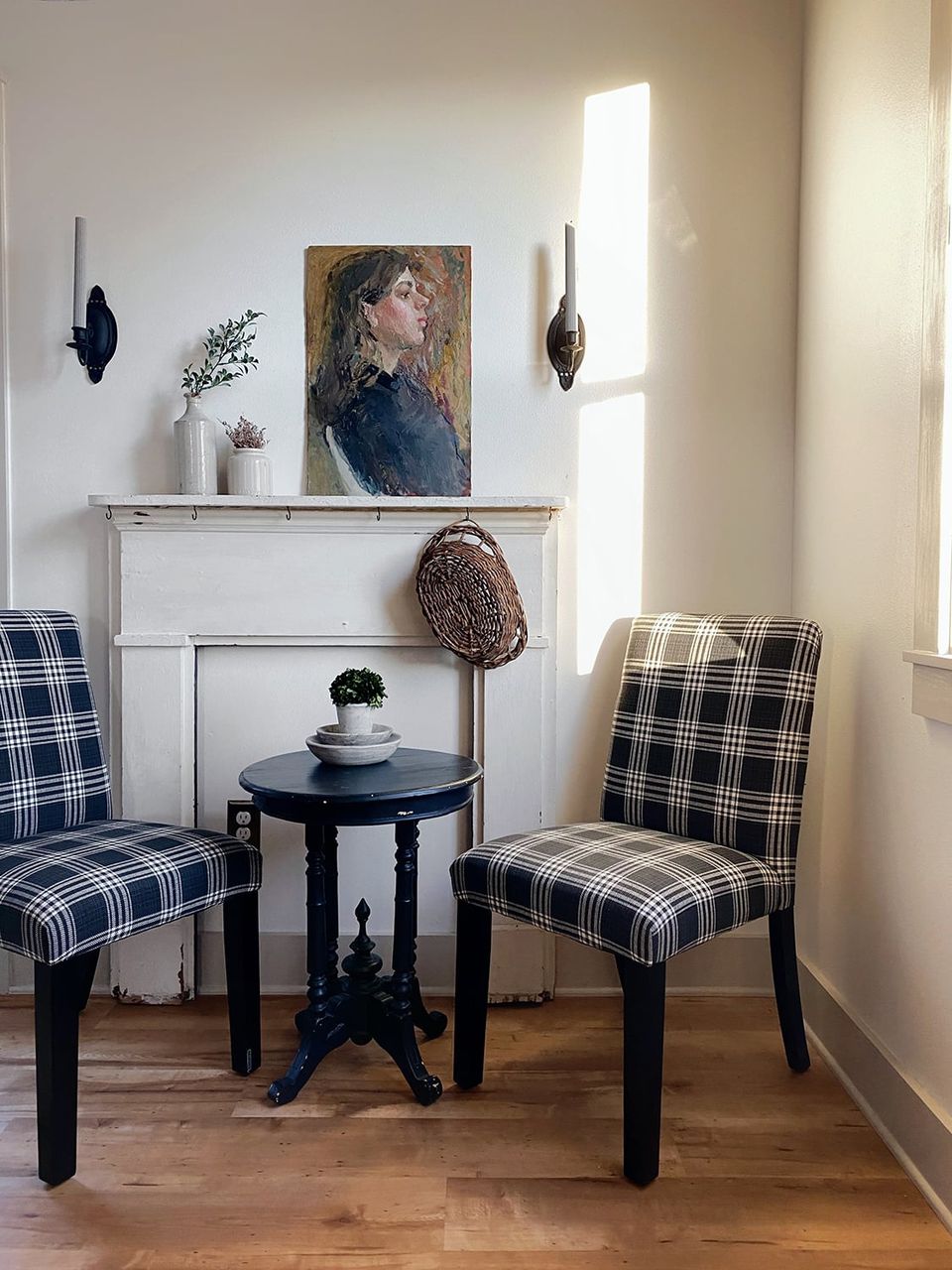 Cozy corner with cream walls, black plaid accent chairs, and dark side table creating classic contrast with warm wood floors