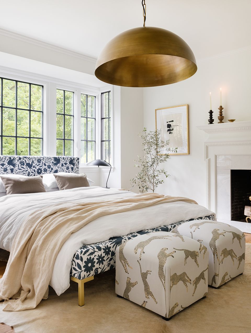 Tranquil bedroom with brass pendant, fireplace, soft neutrals, and botanical touches.
