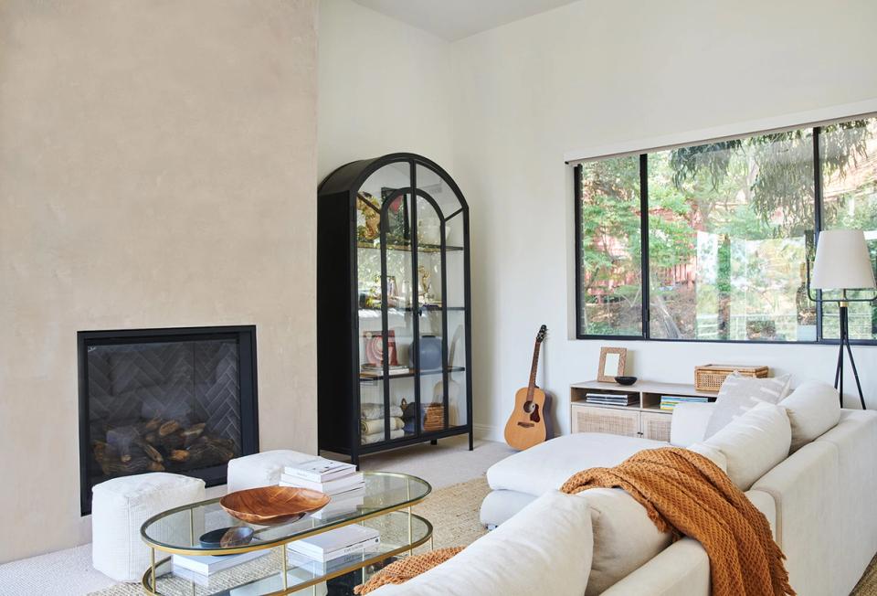 Airy modern living space with cream furnishings, black accents, and strategic negative space highlighting key pieces