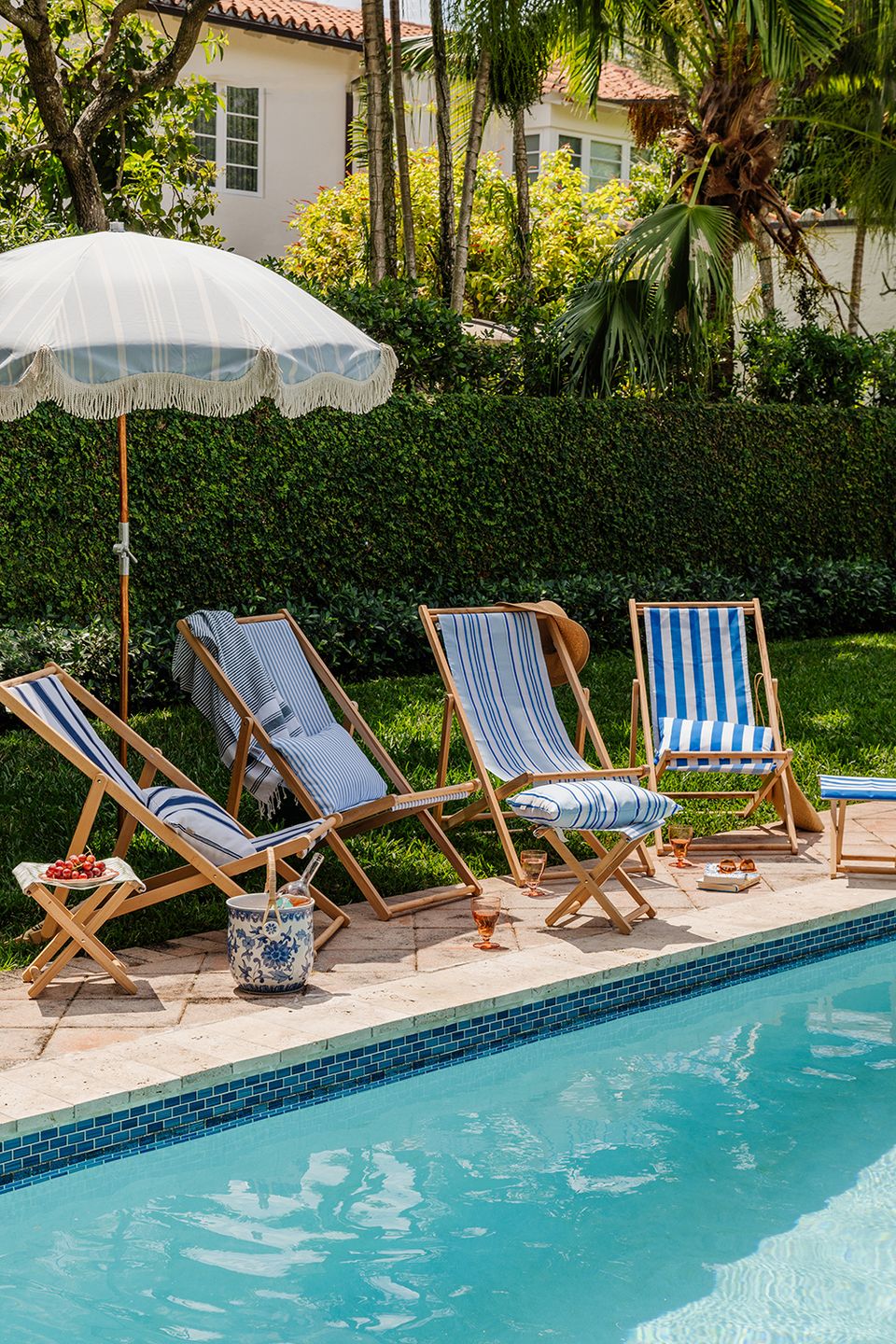 Classic poolside cabana mood with vintage striped lounge chairs and cream umbrella