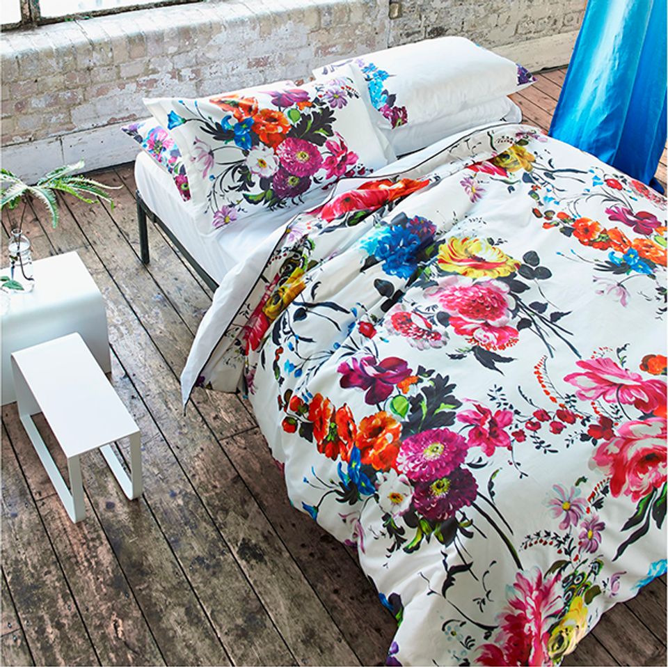Vibrant floral bedding with bold pinks, blues, and yellows on white duvet and pillows