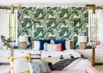 Tropical bohemian bedroom with bold botanical wallpaper, brass four-poster bed, and vibrant jewel-tone accents